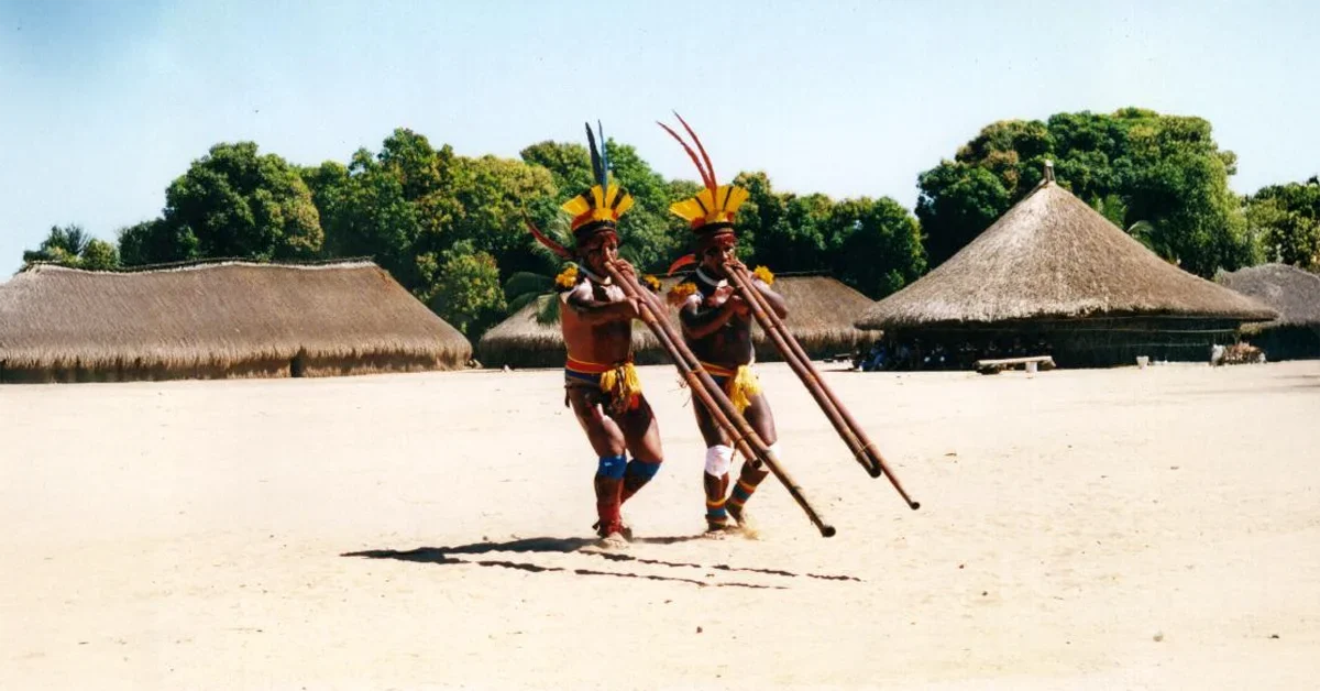 Indigenous brazilian group Kamaiurá playing tipical flute called uruá.